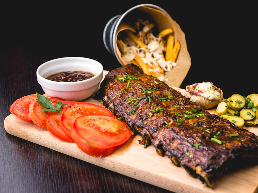 Wood-fired lamb carved on a serving board with tomato and herbs