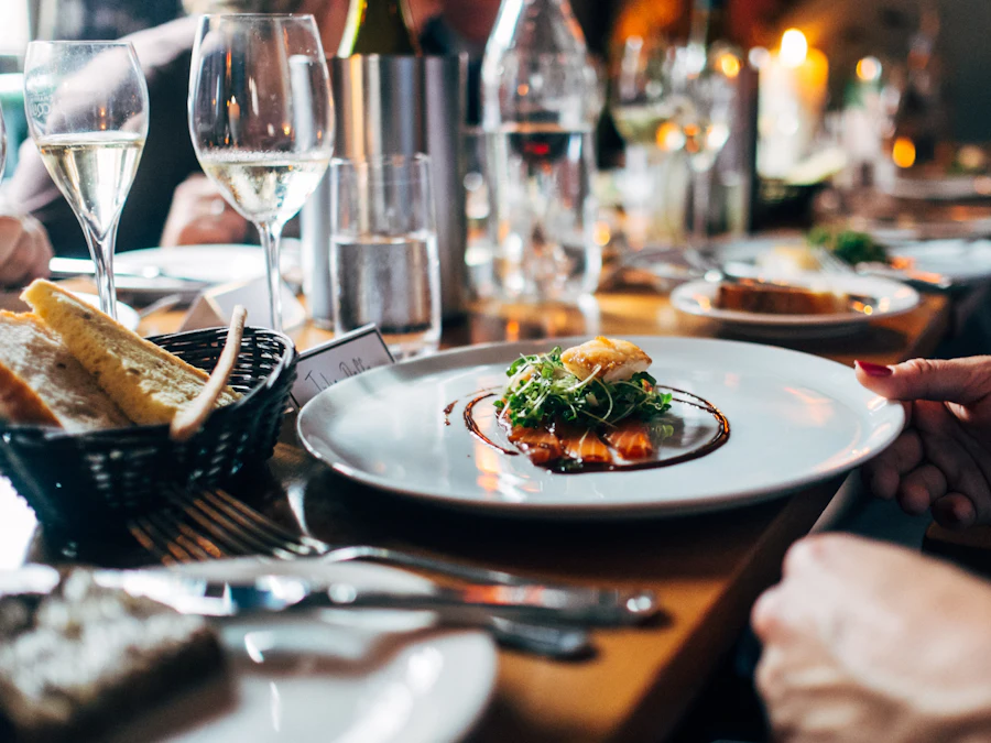 A plate being set down by candlelight, wine glasses in the foreground
